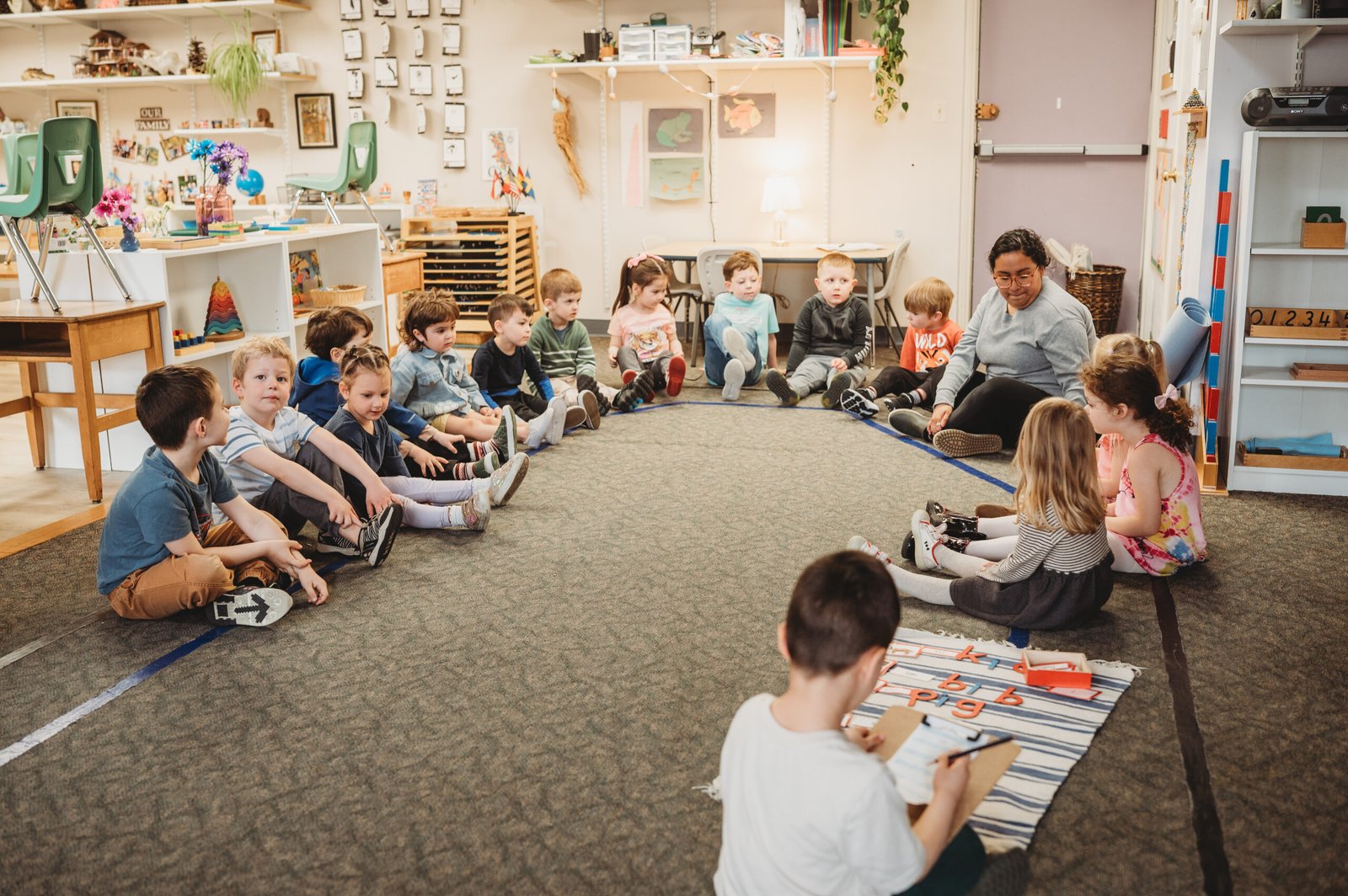 Montessori teacher leading circle time activity with engaged preschool children
