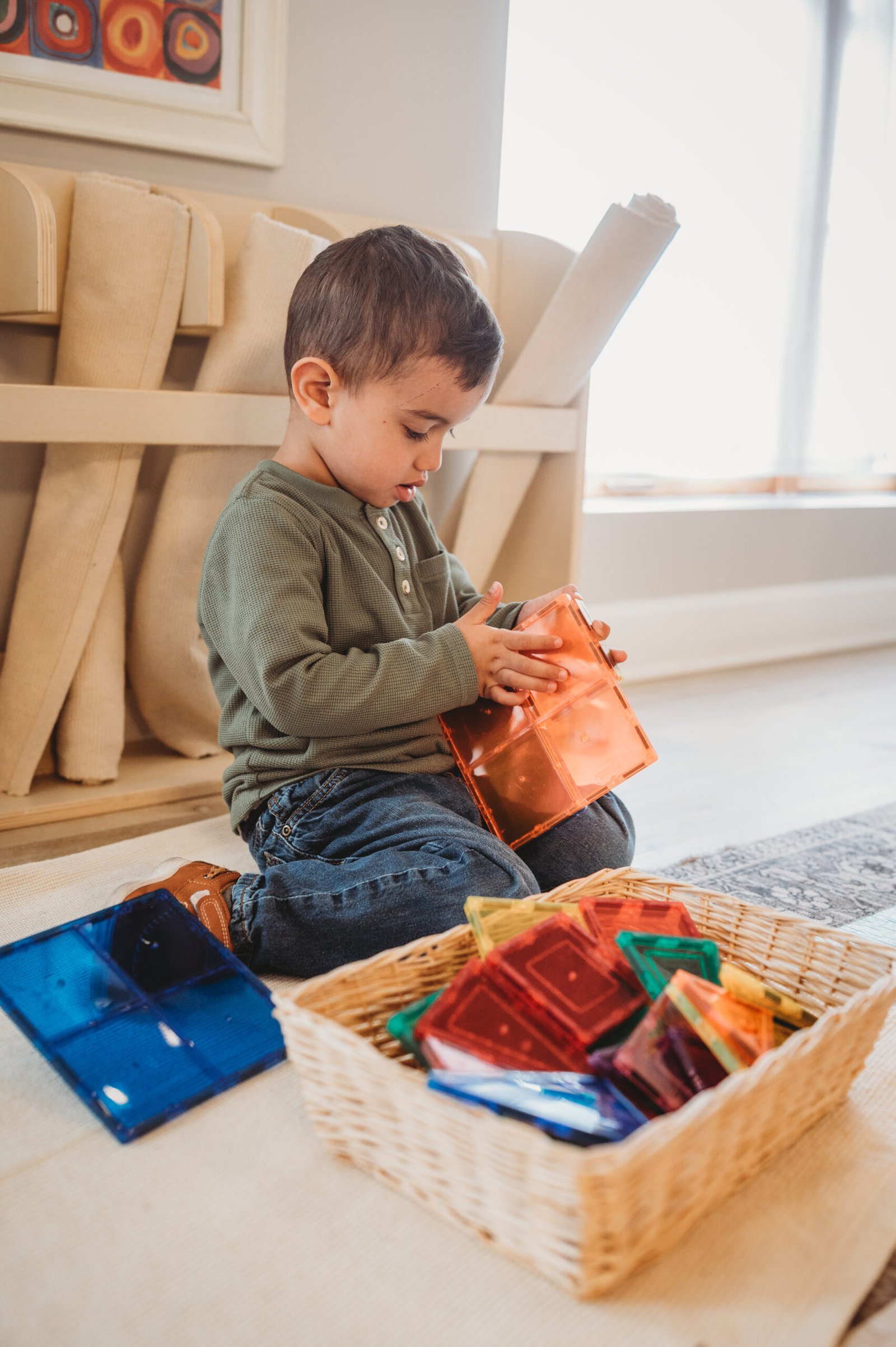 Young boy independently exploring magnetic tiles in Montessori classroom